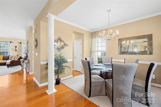 dining space featuring ornate columns, crown molding, a chandelier, and light wood-type flooring