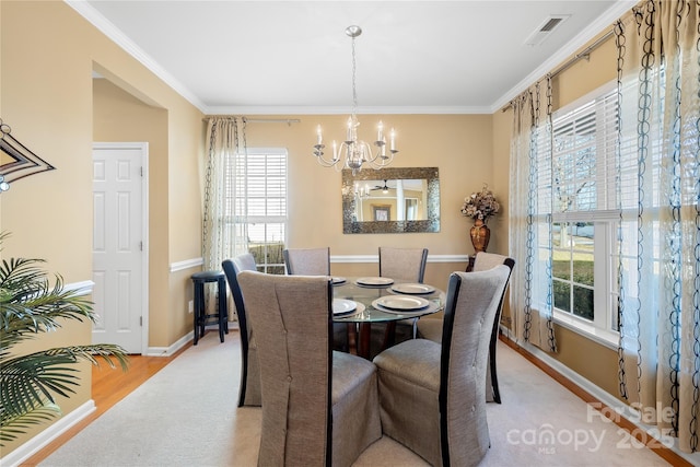 dining room with an inviting chandelier, crown molding, and light wood-type flooring