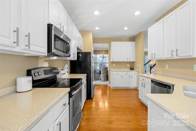 kitchen with light wood-type flooring, white cabinets, and appliances with stainless steel finishes