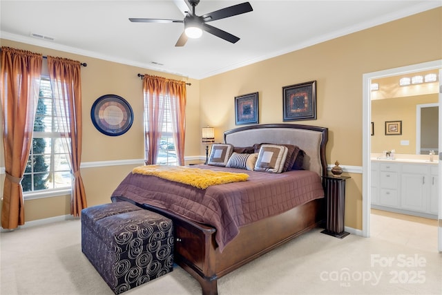 bedroom with crown molding, light carpet, ceiling fan, and ensuite bath