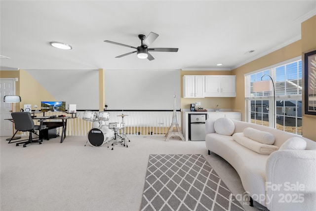 carpeted living room with ceiling fan, ornamental molding, and sink