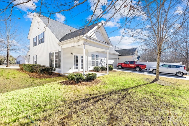 view of side of property featuring a garage, a lawn, and french doors