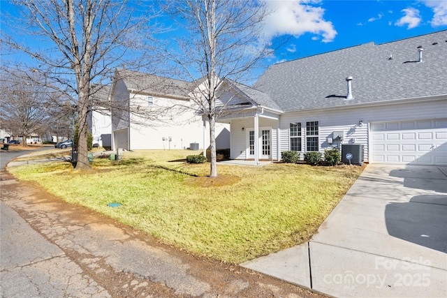 rear view of property featuring a garage, central AC unit, and a lawn