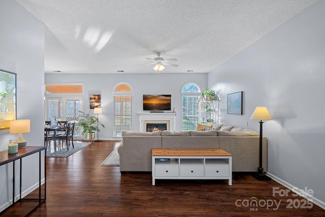 living room featuring dark wood-type flooring, a textured ceiling, and plenty of natural light