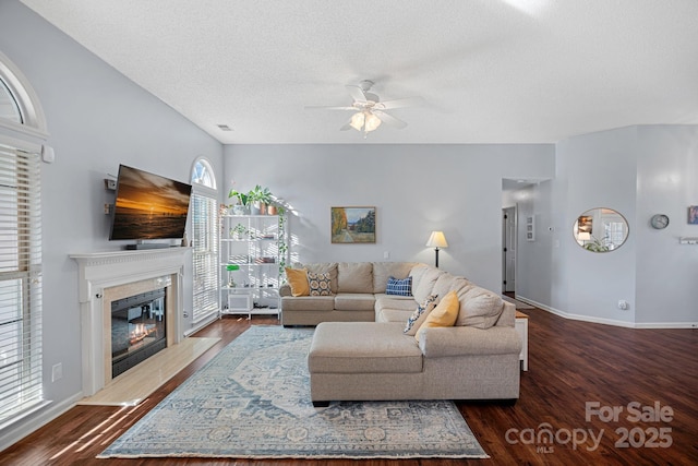 living room with a premium fireplace, dark wood-type flooring, ceiling fan, and a textured ceiling