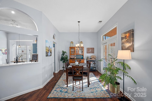 dining area featuring ceiling fan with notable chandelier, a textured ceiling, dark hardwood / wood-style floors, and a healthy amount of sunlight