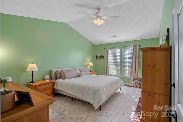 bedroom with lofted ceiling, a textured ceiling, and ceiling fan