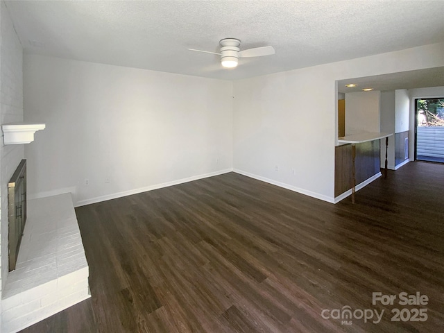 unfurnished living room with a fireplace, dark wood-type flooring, a textured ceiling, and ceiling fan