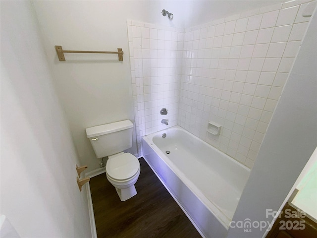 bathroom with hardwood / wood-style flooring, tiled shower / bath, and toilet