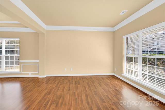 empty room featuring ornamental molding and hardwood / wood-style floors