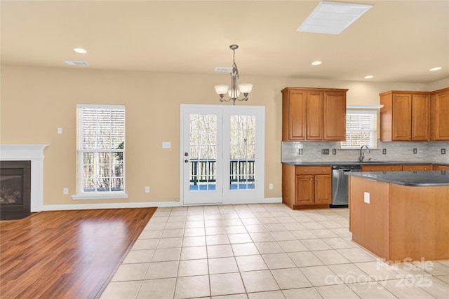 kitchen with decorative light fixtures, dishwasher, sink, backsplash, and a notable chandelier