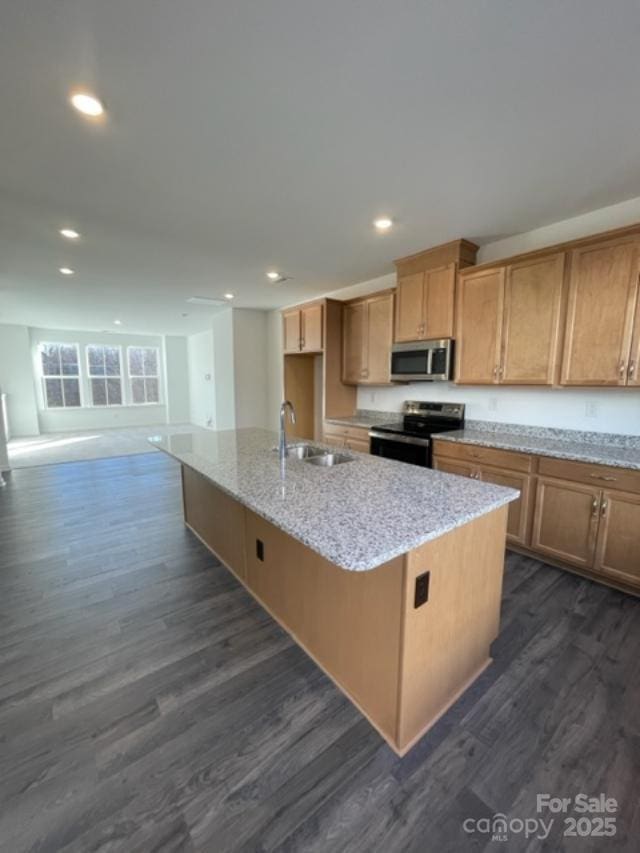 kitchen featuring dark wood-type flooring, stainless steel appliances, sink, and a kitchen island with sink