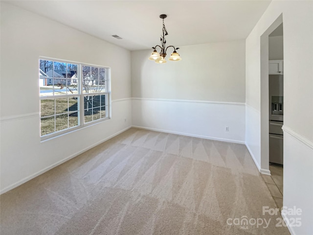 spare room featuring light colored carpet and an inviting chandelier