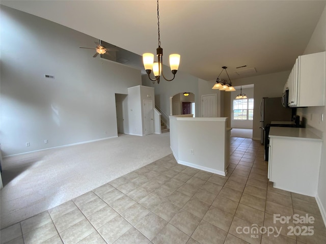 kitchen featuring ceiling fan with notable chandelier, decorative light fixtures, white cabinets, stove, and light colored carpet