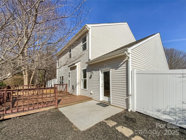 back of house featuring a wooden deck and a patio