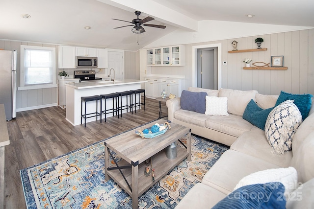 living room with dark hardwood / wood-style flooring, ceiling fan, sink, and vaulted ceiling with beams