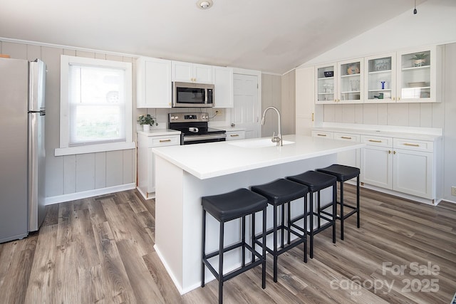 kitchen with an island with sink, appliances with stainless steel finishes, white cabinets, and a kitchen breakfast bar