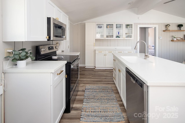 kitchen with vaulted ceiling with beams, dark wood-type flooring, stainless steel appliances, white cabinets, and sink