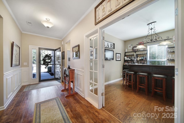 entryway featuring ornamental molding, indoor bar, and dark wood-type flooring