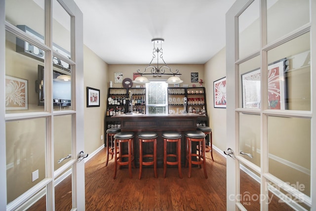 dining space featuring french doors, bar, and dark wood-type flooring