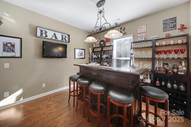 bar with pendant lighting and hardwood / wood-style floors