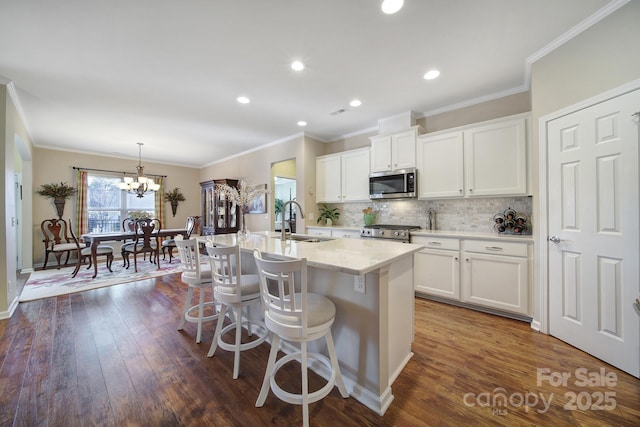 kitchen featuring white cabinetry, stainless steel appliances, a kitchen island with sink, and a breakfast bar area