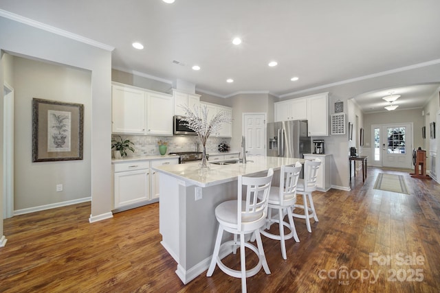 kitchen featuring appliances with stainless steel finishes, a kitchen bar, a kitchen island with sink, and white cabinets