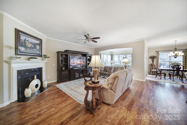 living room featuring crown molding, dark hardwood / wood-style flooring, and ceiling fan with notable chandelier