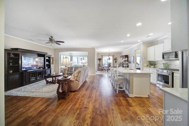 living room with sink, crown molding, dark wood-type flooring, and ceiling fan