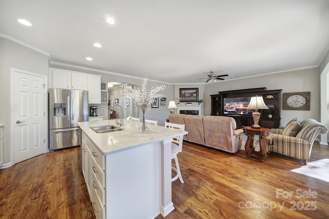 kitchen with sink, white cabinetry, a kitchen island with sink, stainless steel refrigerator with ice dispenser, and wood-type flooring