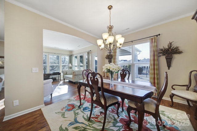 dining space with an inviting chandelier, ornamental molding, a healthy amount of sunlight, and dark hardwood / wood-style flooring