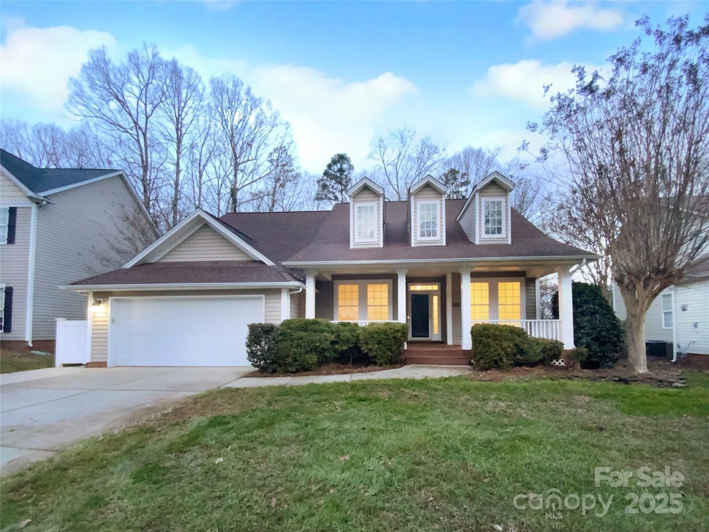 cape cod-style house with a garage, covered porch, and a front lawn