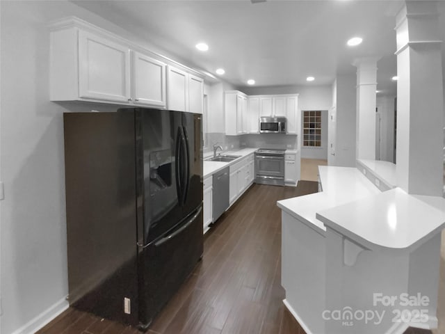 kitchen featuring sink, white cabinetry, stainless steel appliances, a kitchen bar, and kitchen peninsula