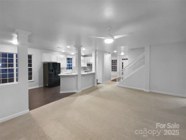 kitchen with ornate columns, white cabinetry, carpet, ceiling fan, and black fridge