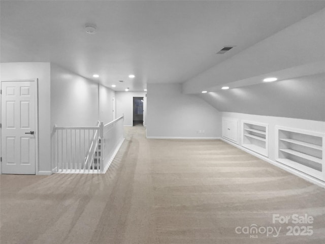 bonus room featuring light colored carpet and built in features