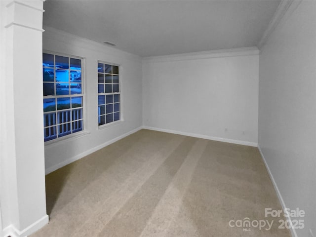 empty room with crown molding, carpet floors, and ornate columns