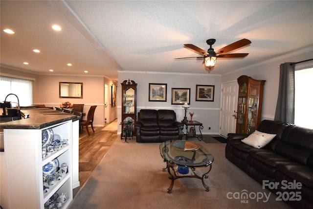 living room with ceiling fan, ornamental molding, light hardwood / wood-style floors, and a textured ceiling