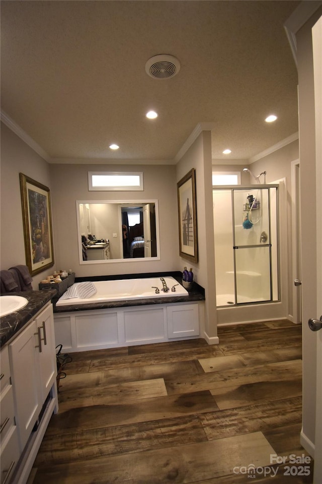 bathroom with independent shower and bath, ornamental molding, hardwood / wood-style flooring, and vanity