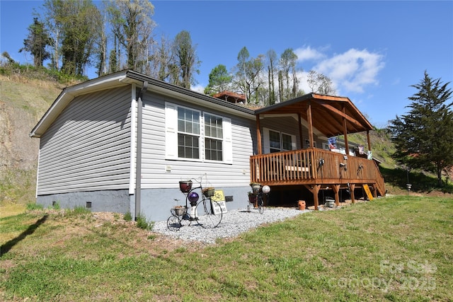 back of house featuring crawl space and a lawn
