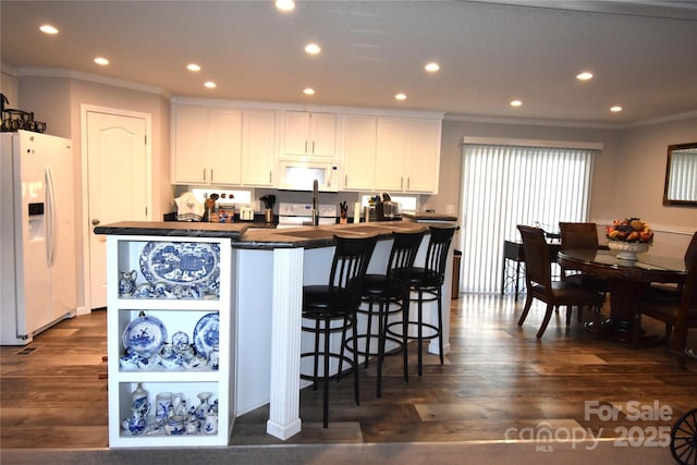 kitchen featuring crown molding, white cabinets, dark countertops, and white appliances