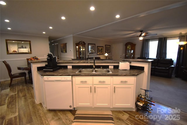 kitchen with dishwasher, a sink, white cabinetry, wood finished floors, and a center island with sink