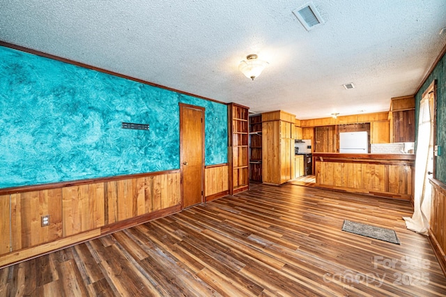 unfurnished living room featuring dark hardwood / wood-style floors, a textured ceiling, and wood walls