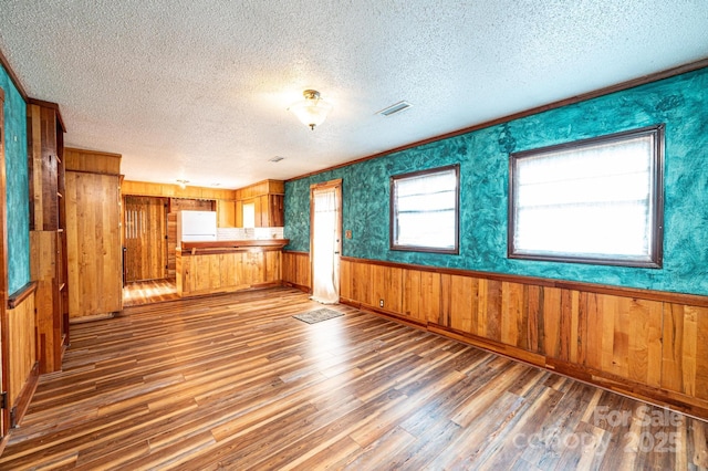 unfurnished living room featuring hardwood / wood-style floors, a textured ceiling, and wood walls