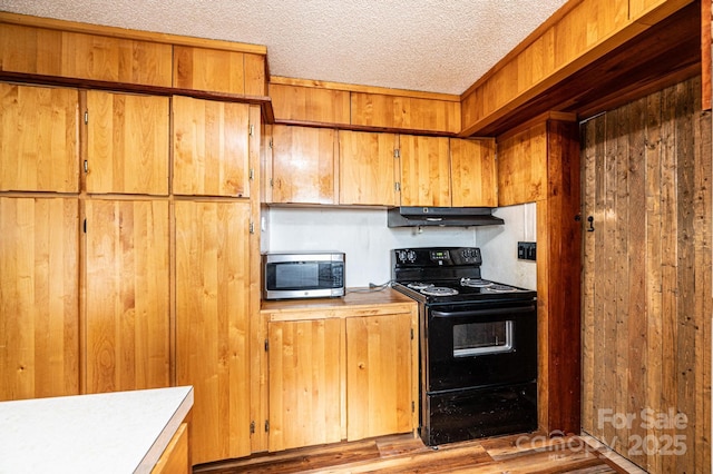 kitchen with black electric range oven, wooden walls, and a textured ceiling