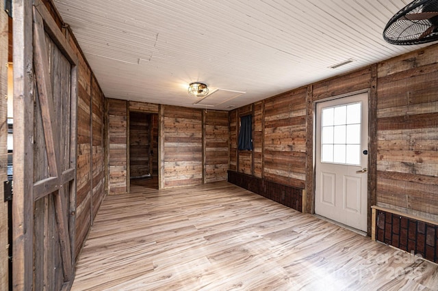 empty room with wood ceiling, light hardwood / wood-style flooring, and wood walls