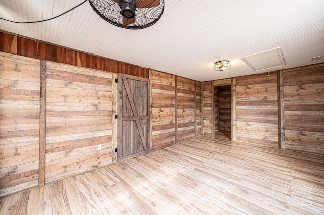 unfurnished room featuring light wood-type flooring and wood walls