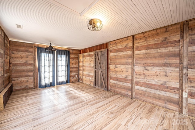 spare room with wooden walls and light hardwood / wood-style floors