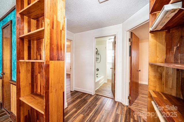 corridor with dark wood-type flooring and a textured ceiling