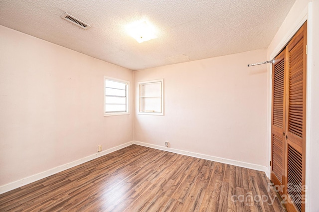 unfurnished bedroom with hardwood / wood-style flooring, a closet, and a textured ceiling