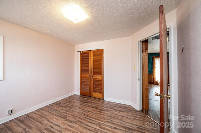 unfurnished bedroom featuring a textured ceiling, dark hardwood / wood-style flooring, and a closet